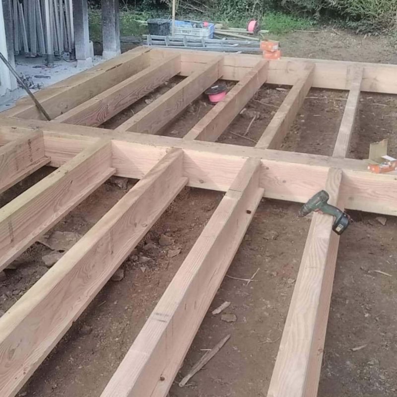 Structure d'un plancher en bois, avec des poutres en bois prêtes à être fixées.