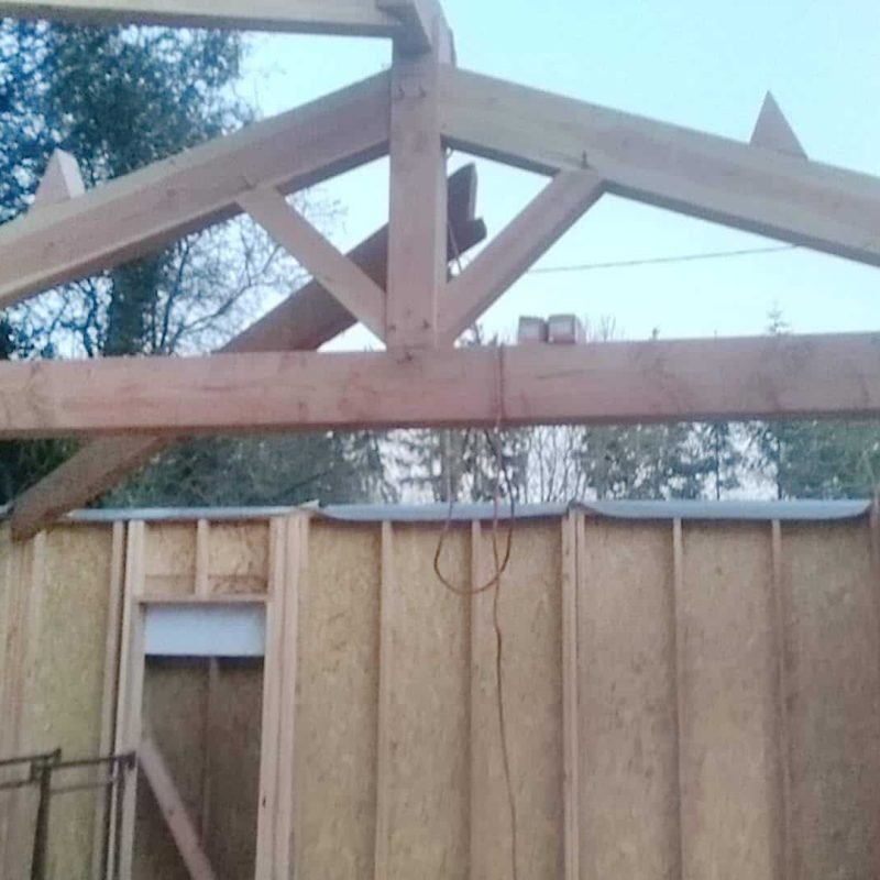 Vue d'une charpente en bois en cours de construction, montrant l'assemblage des poutres.