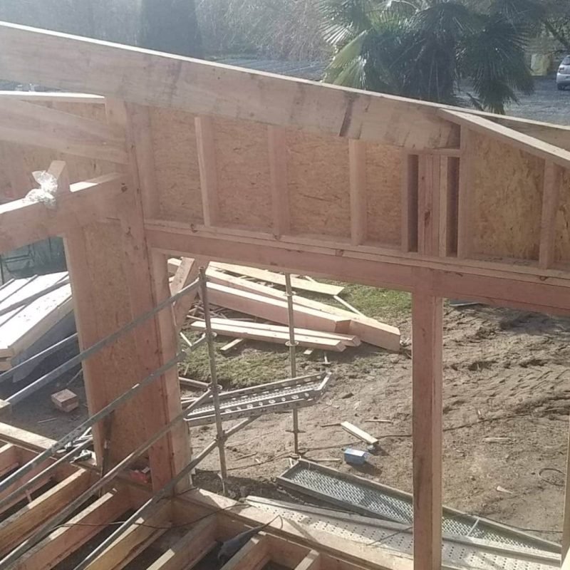 Travaux de construction d'une charpente en bois sur un chantier avec échafaudages.