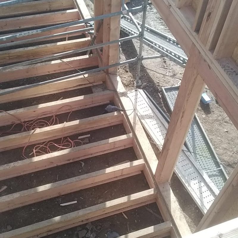 Installation des solives en bois pour le plancher d'une structure en construction.