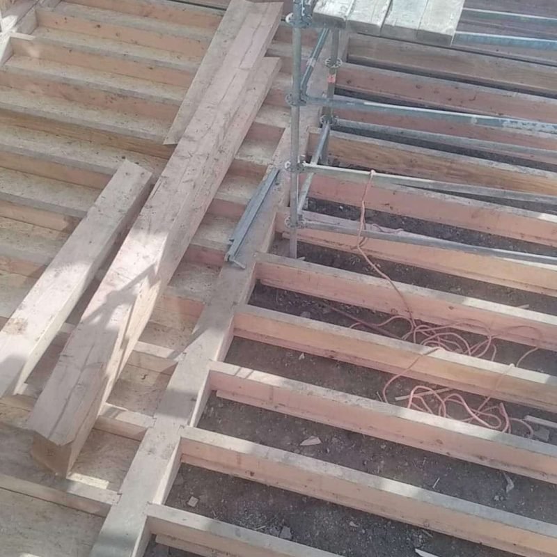 Construction du plancher en bois avec solives et échafaudages en cours de chantier.