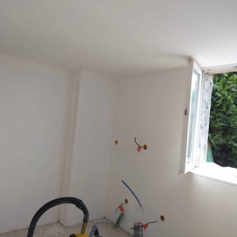 Vue d'une pièce rénovée avec un aspirateur et des outils au sol