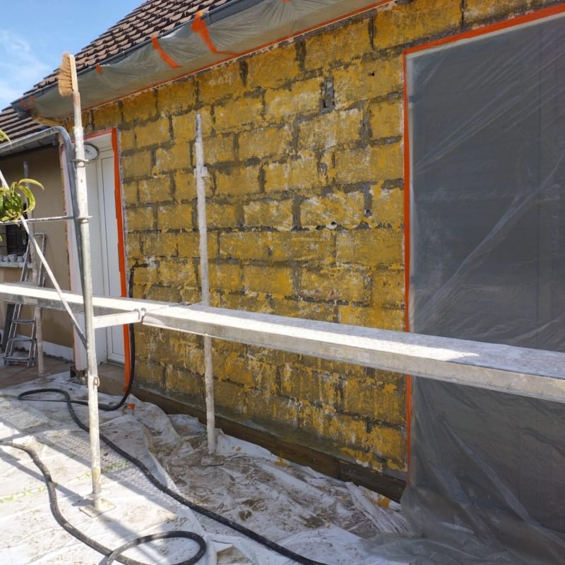 Mur extérieur d'une maison en pierre avec échafaudage installé, en préparation pour la rénovation de la façade