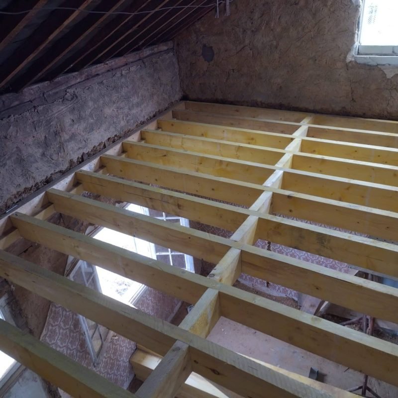 Construction intérieure avec la pose de nouvelles poutres en bois pour créer un étage supplémentaire dans une pièce en rénovation.