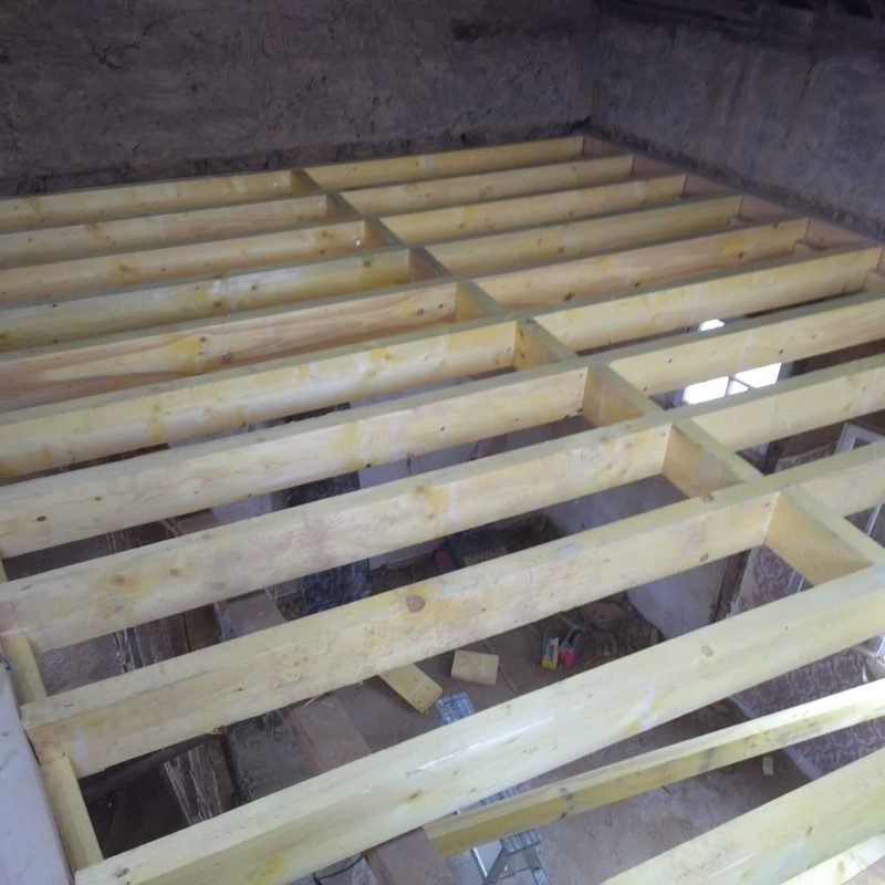 Construction intérieure avec la pose de nouvelles poutres en bois pour créer un étage supplémentaire dans une pièce en rénovation.