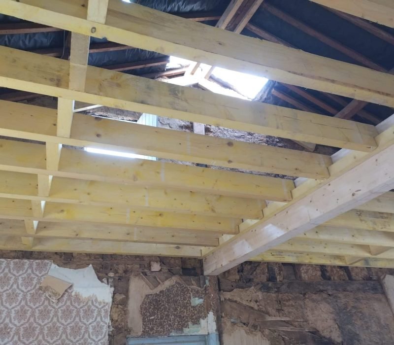 Rénovation du toit avec des ouvertures apparentes et poutres en bois Travaux de rénovation d'une toiture avec des poutres en bois visibles et des ouvertures créées pour rétablir la structure du toit. Travaux de rénovation d'une toiture avec des poutres en bois visibles et des ouvertures créées pour rétablir la structure du toit.