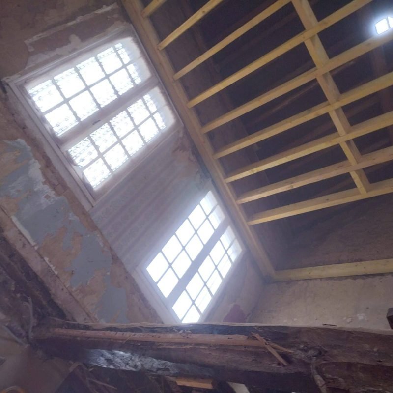 Plafond avec poutres apparentes en bois dans une pièce en cours de restauration